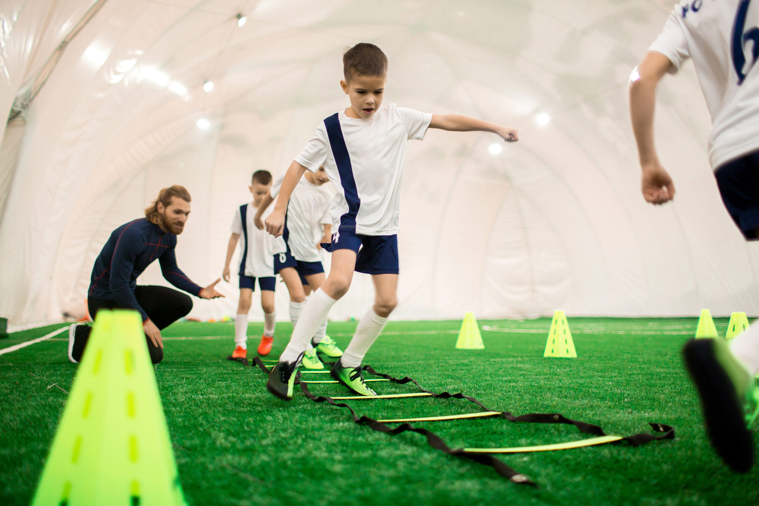 Young boys in uniform exercising on green lawn while preparing for important football game