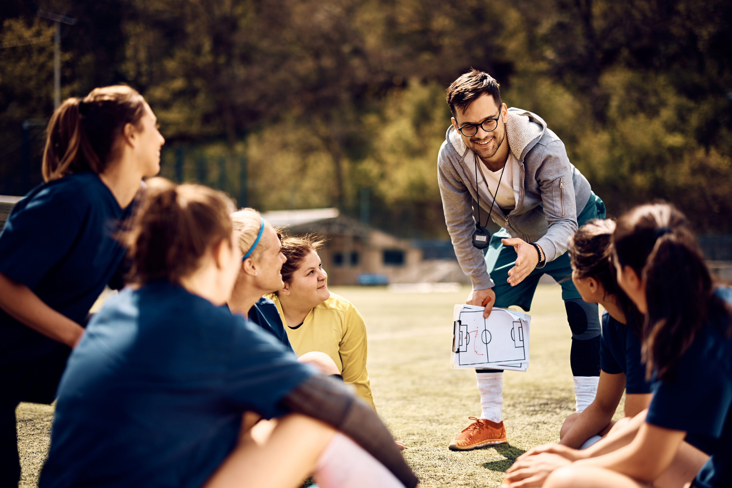 Soccer coach talking while planning game strategy with female player at the stadium.